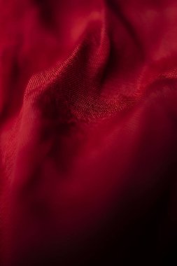 Lüks kırmızı bir kumaşın yakın çekim görüntüsü zengin dokusunu ve koyu kırmızı rengini gözler önüne seriyor. Görüntü, tekstilin ince kıvrımlarını ve dokumasını vurguluyor. Tasarım projeleri için sofistike ve etkileyici bir zemin oluşturuyor.