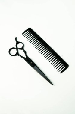 Minimalist bir kompozisyonda keskin siyah kuaför makasları ve el değmemiş beyaz bir fonda zarif bir şekilde düzenlenmiş bir tarak bulunur. Aletler, modern bir kuaför salonu estetiği için mükemmel bir duyarlılık ve stil yayıyor.