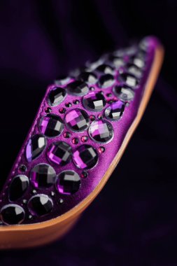 Pırıl pırıl elmas elmaslarla süslenmiş lüks mor bir ayakkabının yakın çekim görüntüsü. Zengin renkler ve karmaşık detaylar göz kamaştırıcı ve zarif bir his yaratır.