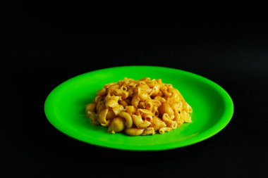 Işıl ışıl yeşil bir tabakta servis edilen pişmiş makarnanın titiz bir yakın plan çekimi. Resim, yiyeceklerle ilgili çeşitli bağlamlarda kullanıma uygun basit ama görsel olarak çekici bir besin sunumu sunmaktadır.