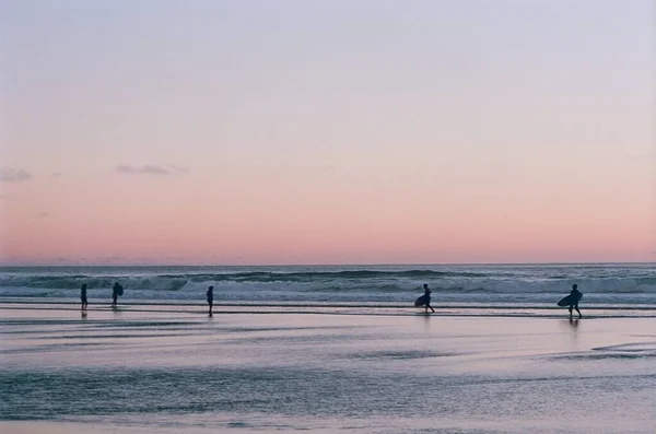 Okyanusta Sörf Yapan Insanların Günbatımı Gökyüzünün Fotoğrafı — Stok fotoğraf