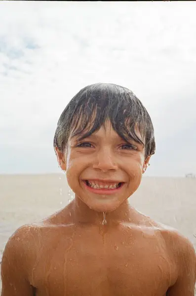 海のシャワーの下に立っている間 幸せな白人少年は微笑んでいます アナログ写真 ストックフォト