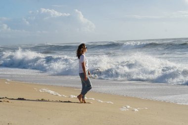 Kumsaldaki esmer kadın, okyanus suyunda yaz gününün tadını çıkarıyor. 