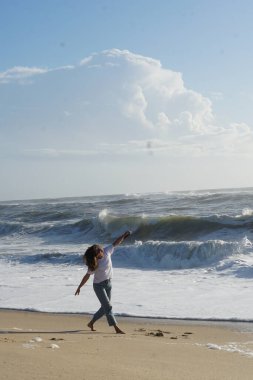 Kumsaldaki esmer kadın, okyanus suyunda yaz gününün tadını çıkarıyor. 