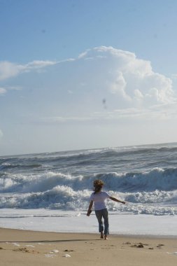 Kumsaldaki esmer kadın, okyanus suyunda yaz gününün tadını çıkarıyor. 