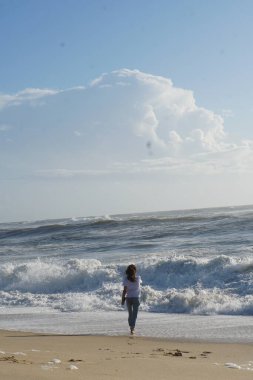 Kumsaldaki esmer kadın, okyanus suyunda yaz gününün tadını çıkarıyor. 