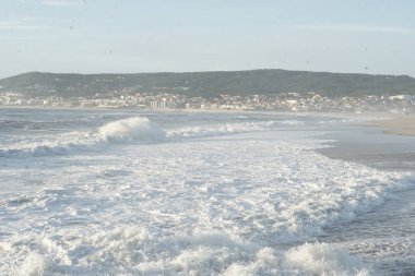 Okyanus dalgaları ve arka planda şehir. Portekiz, Figueira da Foz