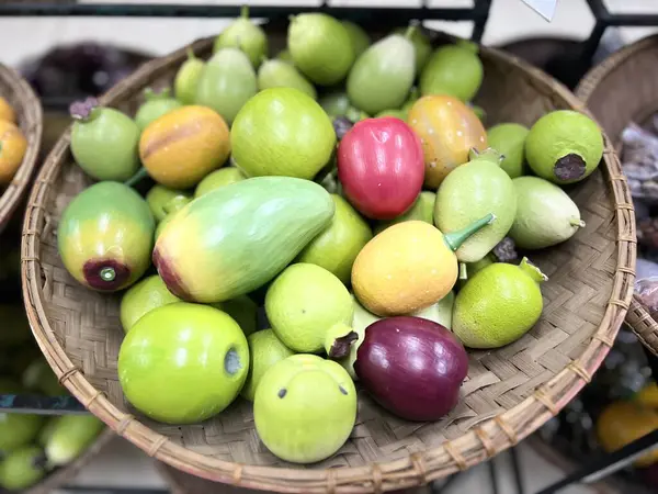 Mango, elma ve guava gibi oyuncak meyveler dokuma bambudan yapılmış bir kabın üzerine konur.