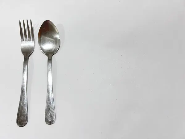 Bir çift eski çatal bıçak takımının fotoğrafı. Etrafında birkaç koyu gölge olan beyaz kağıt üzerinde.