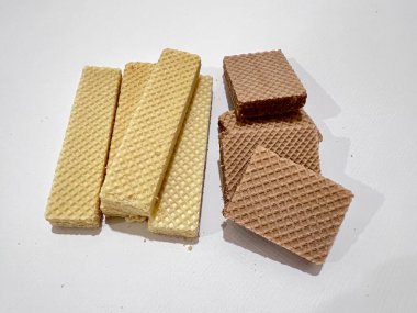 Birkaç vanilya ve çikolata aromalı gofret keki ve beyaz kağıda birkaç kırıntı.