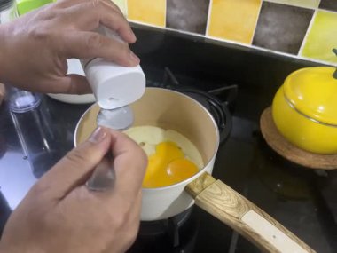 Bir adam yumurtalara biraz tuz ekler ve onları kızartır.