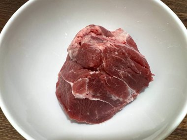 Taze çiğ et sapı, bulaşık yapmak için malzemeler. Beyaz bir seramik kasede, ahşap bir masanın üzerinde..