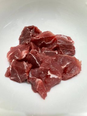 Taze çiğ bifteğin dikey fotoğrafı, pişirme malzemesi. Küçük parçalara bölünmüş. Beyaz arkaplanda izole