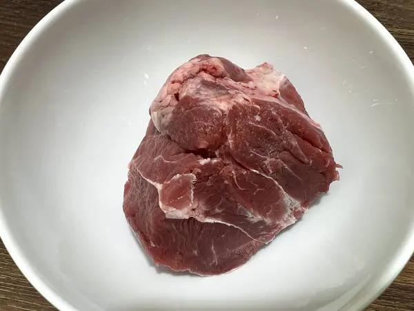 Taze çiğ et sapı, bulaşık yapmak için malzemeler. Beyaz bir seramik kasede, ahşap bir masanın üzerinde..