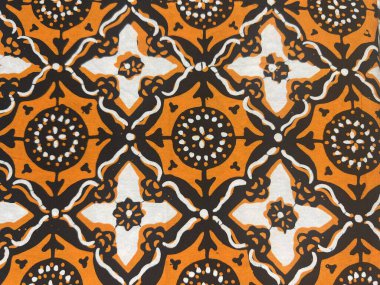 Turuncu arka planda soyut motiflerle geleneksel Endonezya batik kumaşının güzelliğinin yatay fotoğrafı.