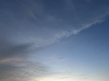 Mavi gökyüzünün güzelliğinin yatay fotoğrafı küçük bir karanlıkla birleştirilmiş, sanki üç parçaya bölünmüş gibi, yumuşak beyaz bulutların dalgaları onu kaplamaya başlıyor..