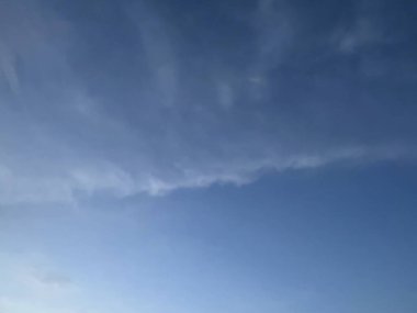 Mavi gökyüzünün güzelliğinin yatay fotoğrafı iki parçaya bölünmüş gibi görünüyor. Yumuşak beyaz bulutlar onu kaplamaya başlıyor..