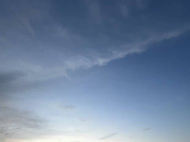 Mavi gökyüzünün güzelliğinin yatay fotoğrafı küçük bir karanlıkla birleştirilmiş, sanki üç parçaya bölünmüş gibi, yumuşak beyaz bulutların dalgaları onu kaplamaya başlıyor..