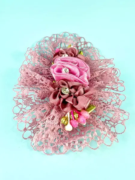 Pembe dantel çiçek motifli saç tokaları. Pembe, yeşil kurdeleler ve elmaslarla karıştır ve eşleştir. Saç aksesuarları, 3 boyutlu. Mavi arka planda izole edilmiş. Sanat ve hobi ilhamı