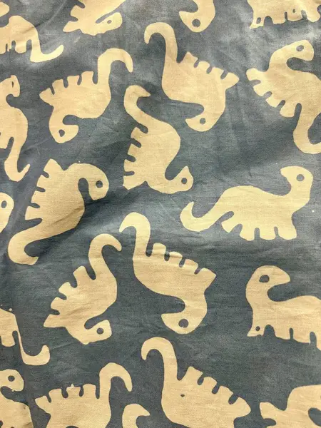Dinozor karikatür motifli Endonezya batik kumaşı. Çocuklar ve bebekler için şirin bir motif. Gri ve pastel sarısı hakimdir. Özgeçmiş ve doku fikirleri için uygun.