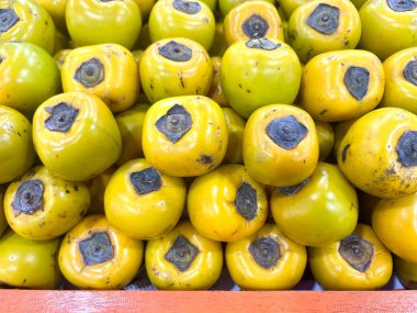 Meyve dükkanında sergilenen bir yığın olgun hurma. Bu fotoğraf kitap kapakları, dergiler, gazeteler, reklamlar, afişler, afişler ve sosyal medya paylaşımları için uygundur..