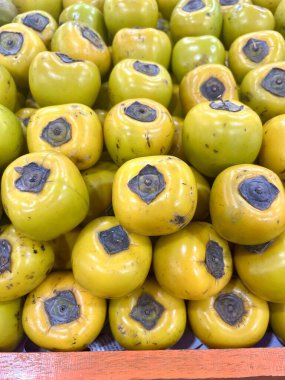 Meyve dükkanında sergilenen bir yığın olgun hurma. Bu fotoğraf kitap kapakları, dergiler, gazeteler, reklamlar, afişler, afişler ve sosyal medya paylaşımları için uygundur..