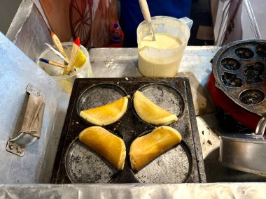 Bir yiyecek satıcısı tavada kue cubit ya da tatlı bir krep pişiriyor. Kue cubit bir Betawi Endonezya spesiyalidir. Un, süt ve çikolata parçacıklarından yapılmış.