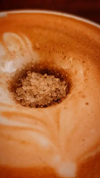 Parçalanmış kamış şekeri kapuçino köpüğünün içinde erir.