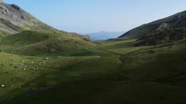 Öğleden sonra insansız hava aracı atışı kayalık dağlar arasındaki yüksek yükseklikte huzurlu yeşil bir düzlük gösteriyor..