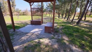 Huzurlu bir parkta, yeşilliklerle çevrili ahşap bir pergola. Yürüyüşçüler ve sporcular için mükemmel bir dinlenme yeri..