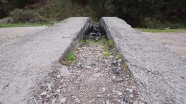 Çöplerle ve terk edilmiş petrollerle dolu, ormanı kirleten ve vahşi yaşam ve doğa için ciddi bir tehlike arz eden eski bir beton yapı..