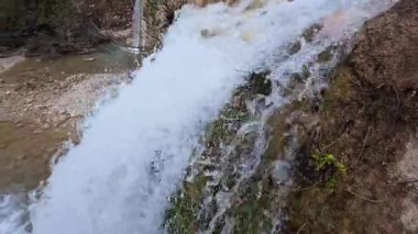 Yavaş çekim kayaların arasından akan suyu yakalar, nehrin içinden çekilen küçük bir şelaleye akar..