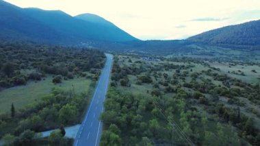 Yunanistan 'dan gelen bu hava görüntüleri, geniş bir Akdeniz ovası boyunca uzanan ve çevresindeki dağlarla çevrili ulusal bir yolu gösteriyor. Arabalar doğal ortamda hareket eder..