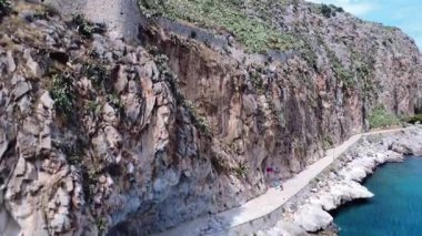 Yunanistan 'da deniz kıyısında engebeli bir dağ antik duvarlar ve manzaralı bir yol barındırıyor. Akdeniz 'de kayalıklar, mavi sular ve tarihi kalıntılar yer alıyor..