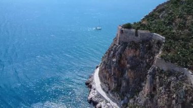 Yunanistan 'da, Ege Denizi' ni aşan bir yelkenli, gözle görülür antik surları olan kayalık bir dağın yakınından geçiyor. Yazın insansız hava aracı tarafından yakalandı..