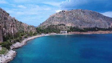 Bu insansız hava aracı görüntüleri, kayalık kayalıklar ve Akdeniz sularıyla çevrili uzak bir Yunan koyunu gösteriyor. Ağaçlar ve kayalar bu sakin manzarada kıyı boyunca uzanır..