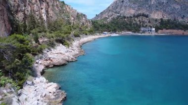 Yunanistan 'ın Nafplio kentinde Akdeniz bitki örtüsü ve dik kayalık yamaçlarla çevrili kayalık bir sahil manzarası.