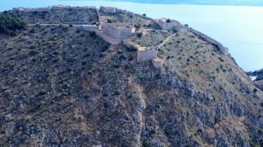 İnsansız hava aracı görüntüsü, Yunanistan 'ın Nafplio kıyı kasabasının üzerindeki antik kaleyi gösteriyor. Kale Akdeniz 'i koruyor ve ziyaretçiler için bir park alanı içeriyor..