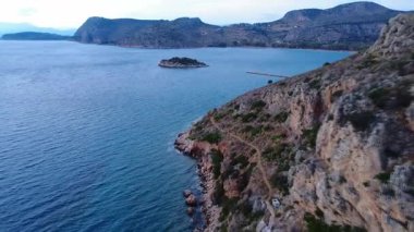 Yunanistan 'da manzaralı bir Akdeniz mevkiinde bir yabani körfez, koruyucu bir deniz duvarı, bir dağ yamacı ve hepsi de yukarıdan görülen bir adacık yer alıyor..