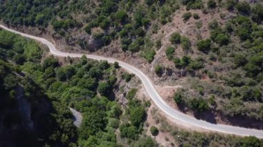 Uzak asfalt yolu, insansız hava aracı tarafından çekilen Yunanistan 'daki bir geçitten geçiyor. Sahneye Akdeniz kayalıkları ve vahşi ağaçlar hakim..