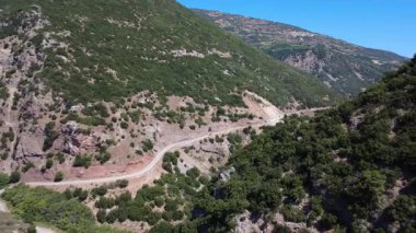 Bu hava görüntüleri Yunanistan 'da bir kanyonun içindeki eğri asfalt bir yolu gösteriyor. Akdeniz arazisi dik ve ormanlıdır..