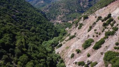 Yunanistan 'da insansız hava aracı tarafından çekilen tehlikeli dolambaçlı yol Akdeniz' deki sık ormanlı uçurumlardan geçerken.