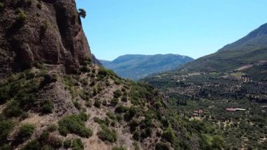 Yunanistan 'daki dik uçurumların üzerinden uçan bir İHA, zeytin korulukları ve dağınık evlerle dolu verimli bir vadiyi ortaya çıkarıyor. Akdeniz manzarası engebeli ve yeşil.