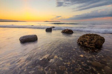 Kayalık bir sahilde gün batımı manzarası. Alor Adası, Doğu Nusa Tenggara - Endonezya