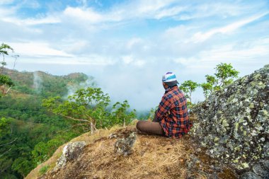 Bir adam tepede oturmuş manzaranın tadını çıkarıyor. Talopi, Alor, Doğu Nusa Tenggara - Endonezya