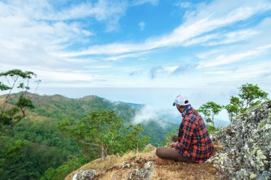 Bir adam tepede oturmuş manzaranın tadını çıkarıyor. Talopi, Alor, Doğu Nusa Tenggara - Endonezya