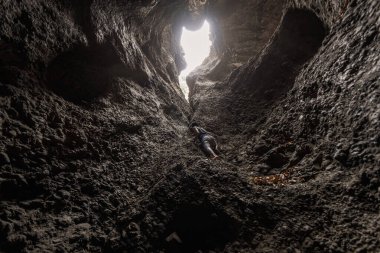 Bir adam mağara duvarından çıkışa doğru tırmanıyor. Alor - Endonezya