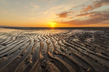 Sahilde gün batımı manzarası alçak gelgitte. Kumun dalgalı bir deseni var gibi görünüyor. Kokar Sahili, Alor, NTT - Endonezya