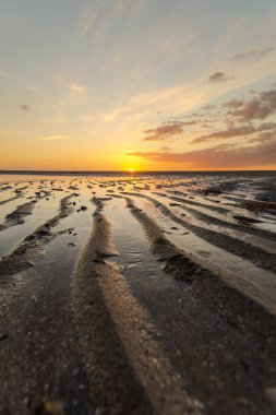 Sahilde gün batımı manzarası alçak gelgitte. Kumun dalgalı bir deseni var gibi görünüyor. Kokar Sahili, Alor, NTT - Endonezya