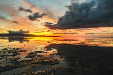 Alçak bir sahilde bulutlu bir günbatımının yansıması. Alor, Doğu Nusa Tenggara - Endonezya